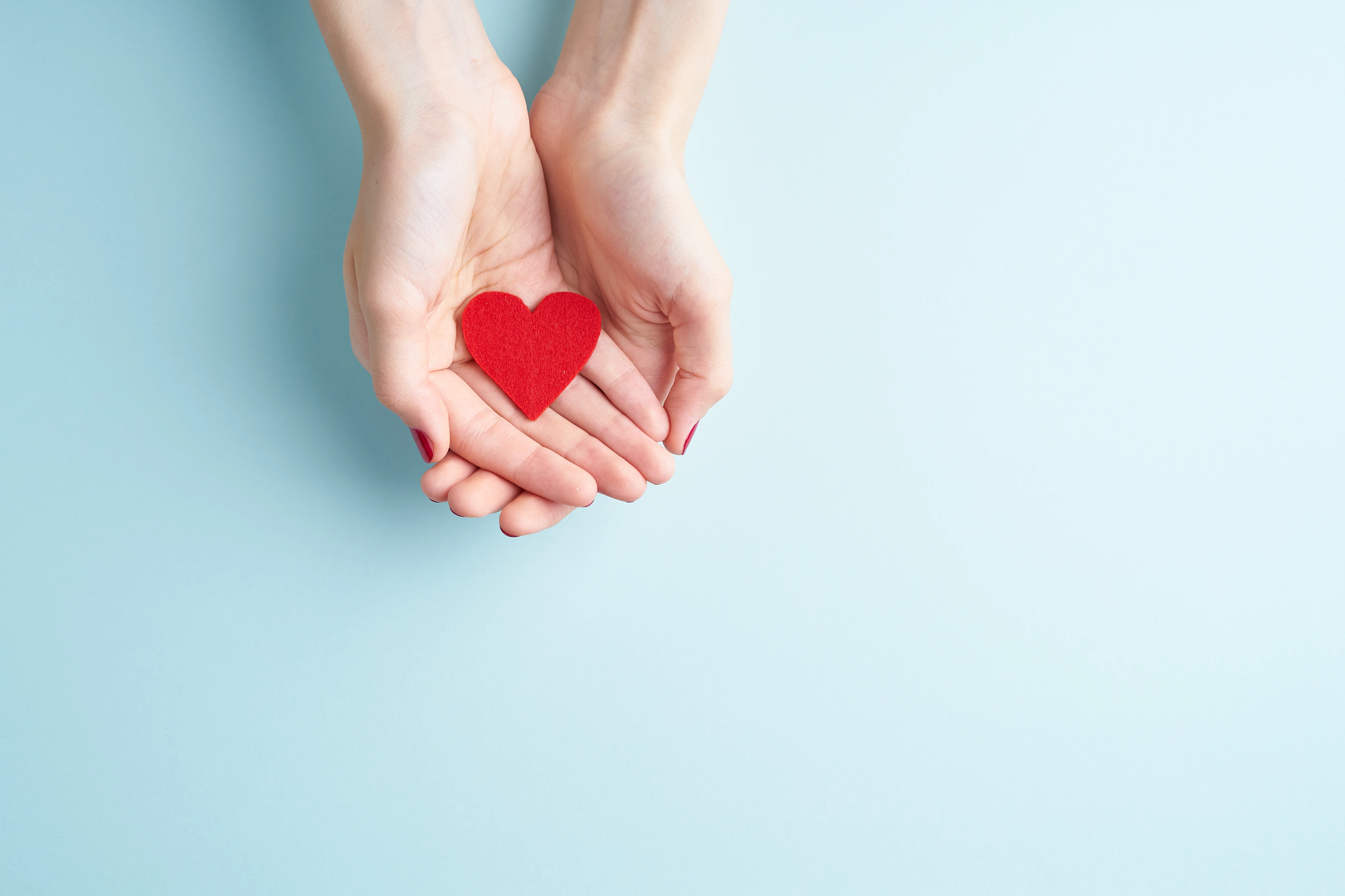 Hands cupped together holding a paper heart.