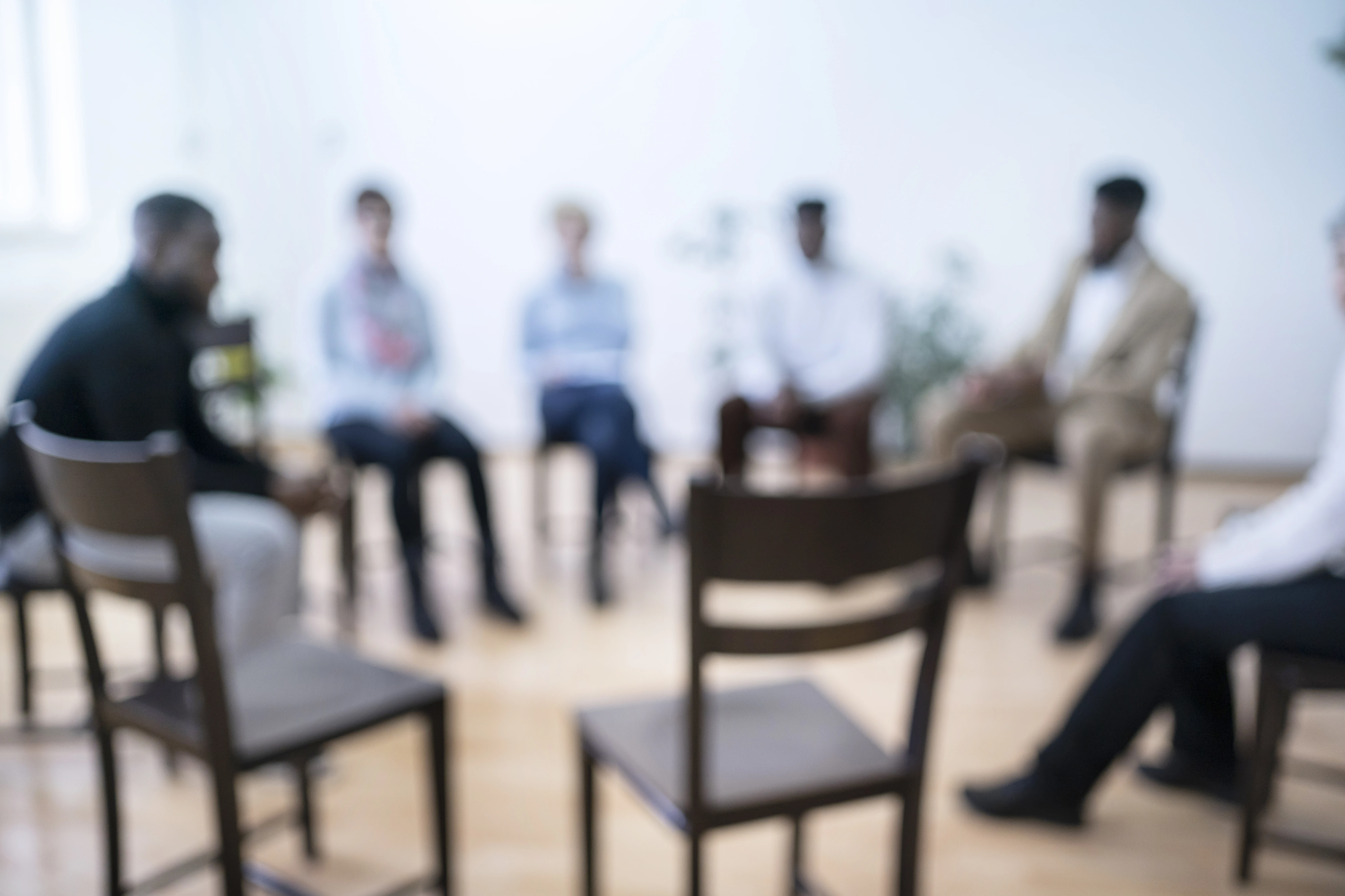 Fuzzy anonymous picture of group meeting with chair pulled out for newcomers.